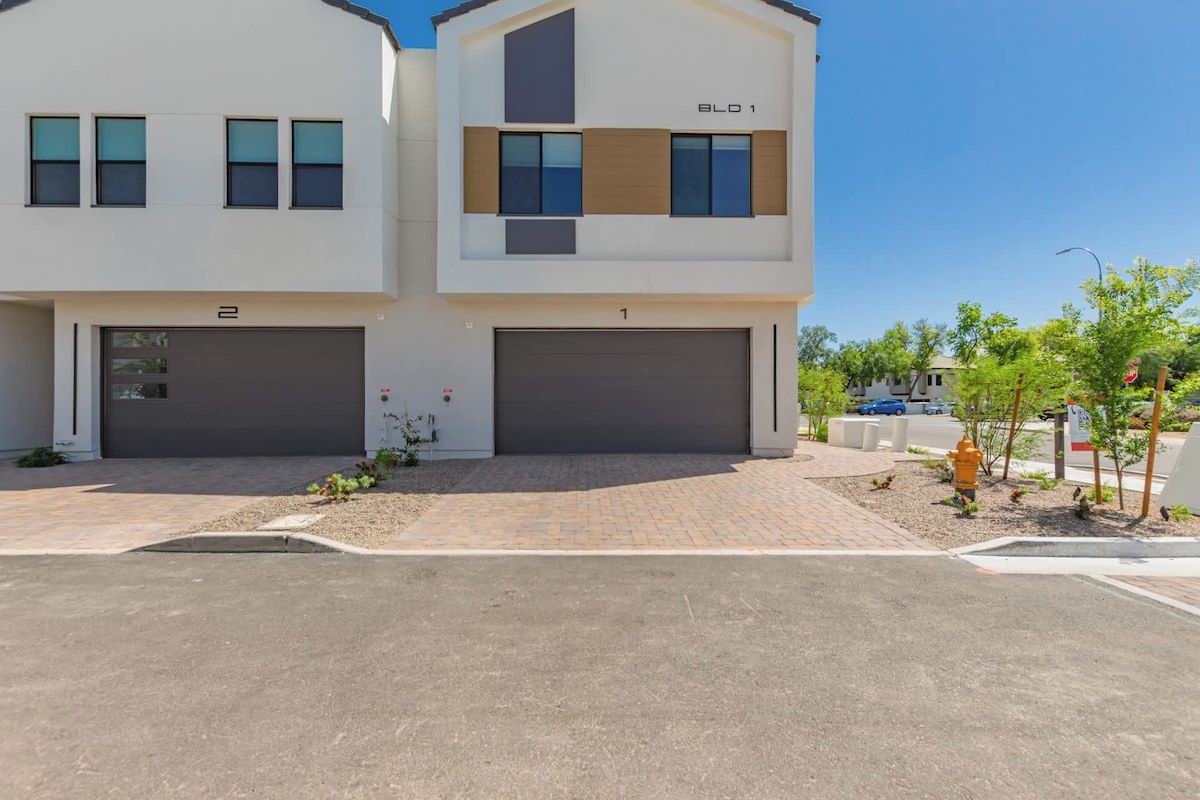 A modern two-story residential building with two garages, a clear driveway, and a well-maintained lawn.