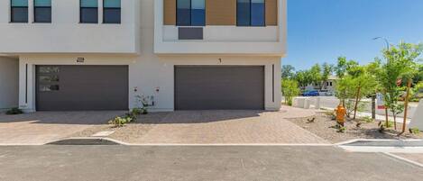 A modern two-story residential building with two garages, a clear driveway, and a well-maintained lawn.