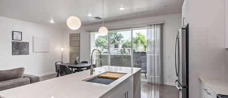 A modern kitchen with a central island, stainless steel appliances, and a dining area with a table and chairs.
