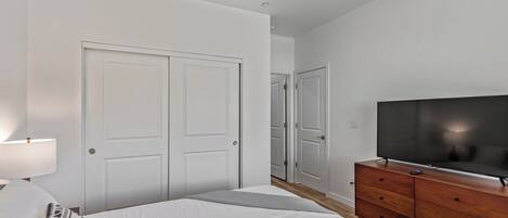 A bedroom with a bed, a dresser, a television, and a door.