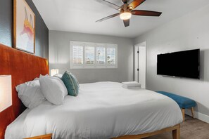 Ein Schlafzimmer mit einem Bett, einem Deckenventilator, einem Fenster und einem Fernseher.