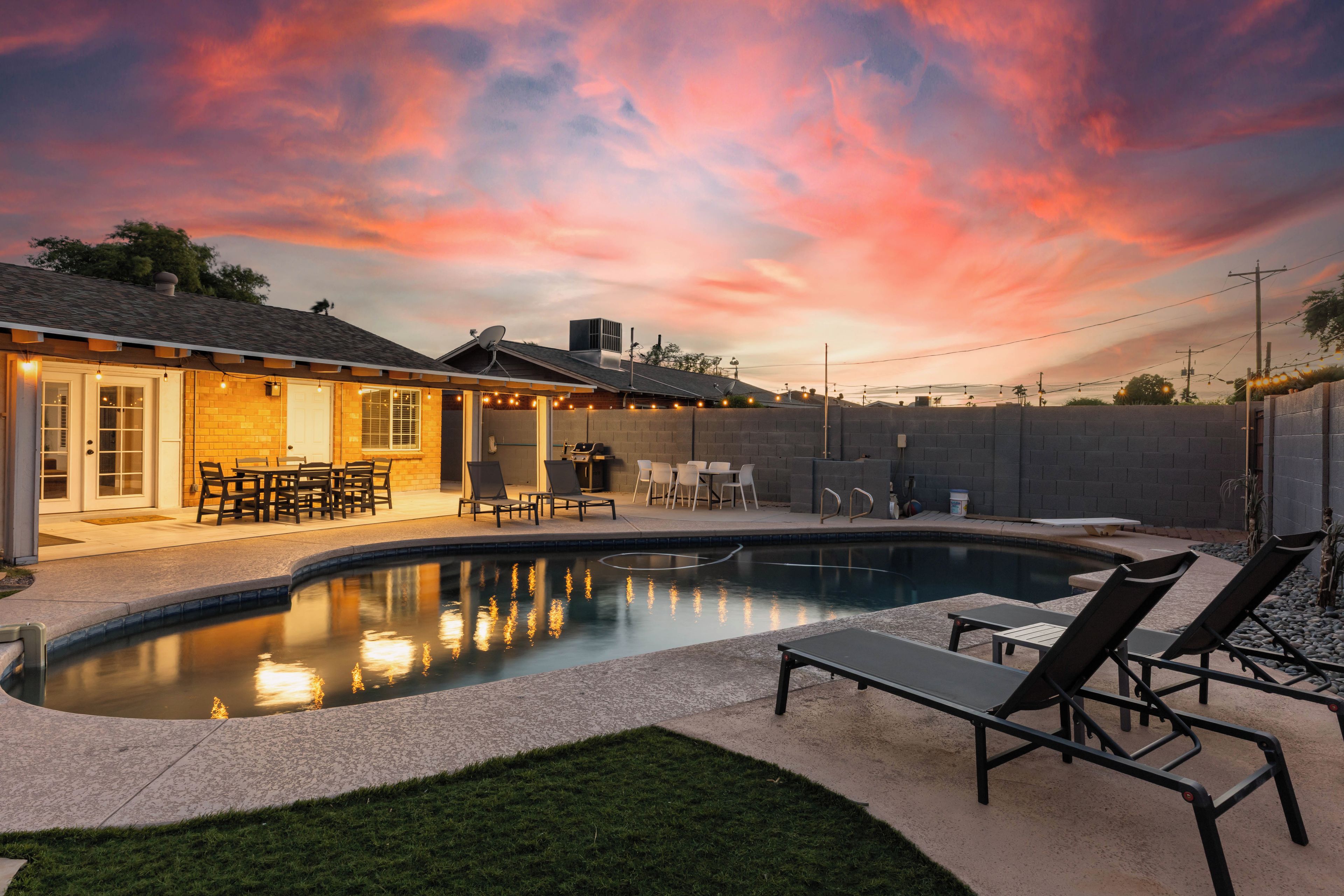 A backyard with a swimming pool, outdoor seating, and a patio area.