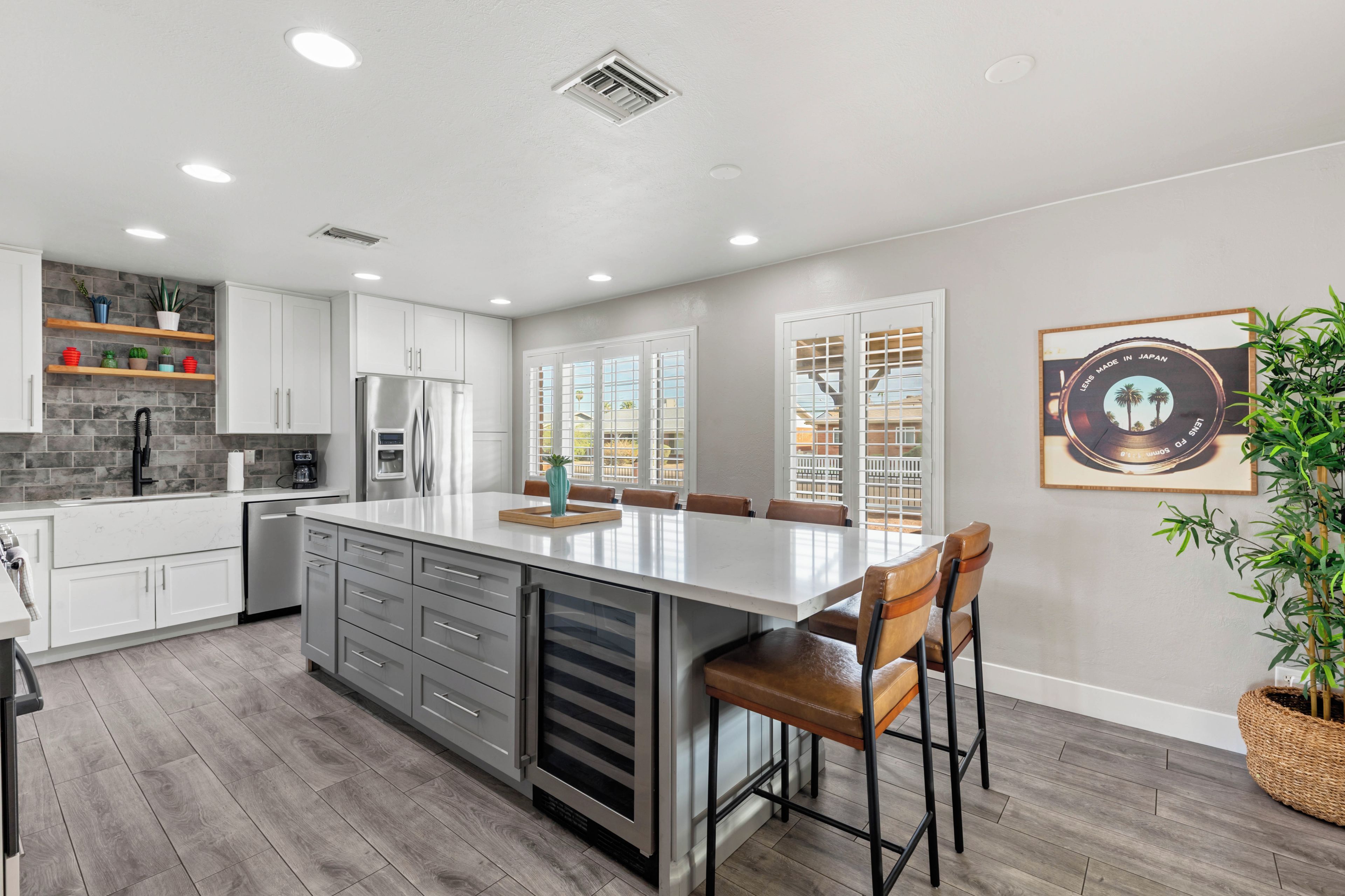 A modern kitchen with a central island, built-in appliances, and a dining area with chairs.