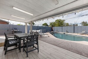 An outdoor patio with a pool, a dining table with chairs, and a barbecue grill. - Scottsdale Retreat with Private Pool | 4BR Home Near Old Town (Scottsdale)