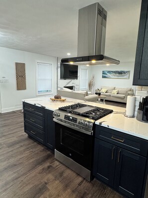 A modern kitchen with a central island, built-in oven, and stainless steel range hood. - Stateline Family Retreat  (South Beloit)