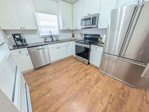 Eine moderne Küche mit Edelstahlgeräten, weißen Schränken und Holzboden.