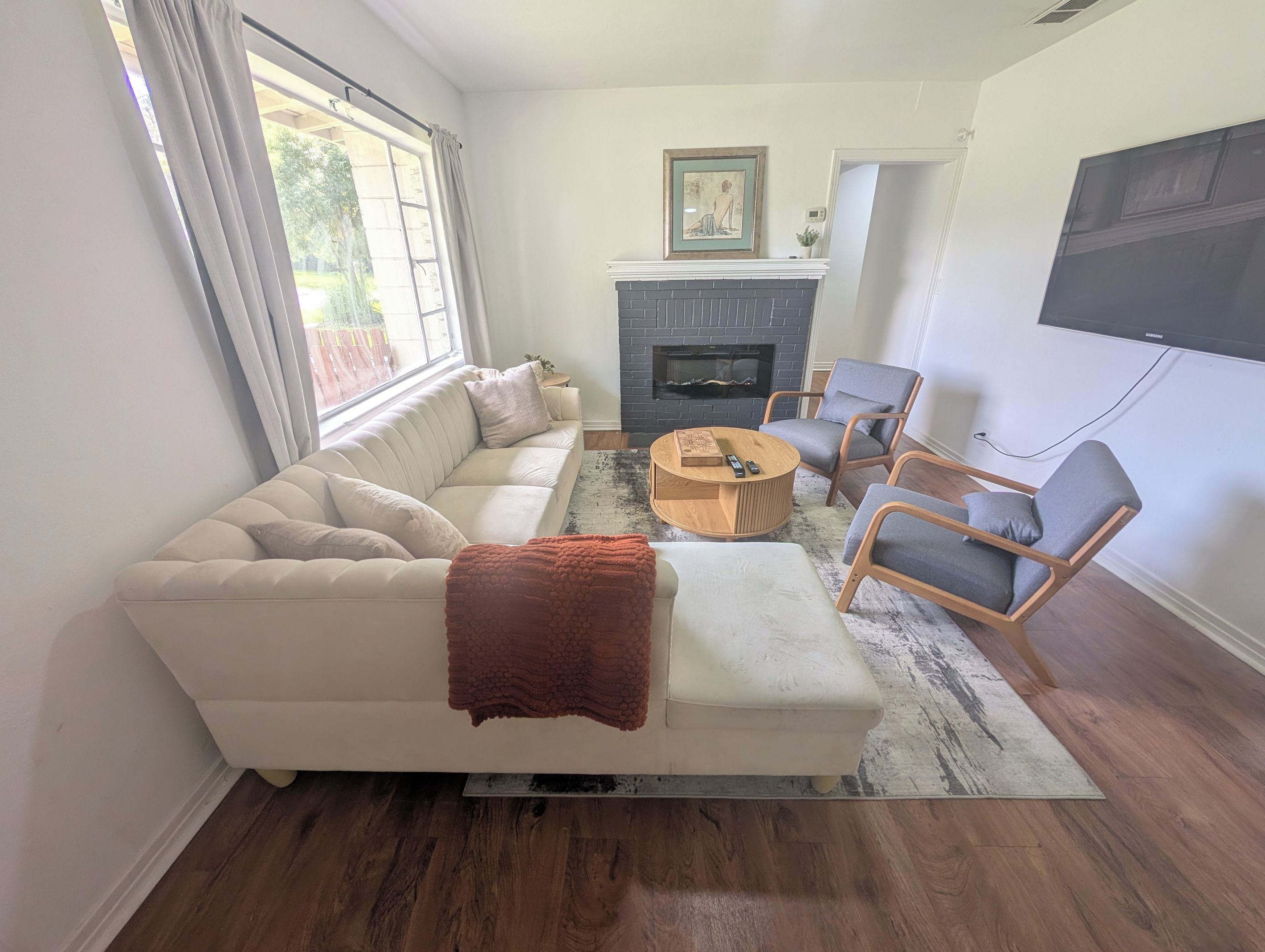 Una sala de estar con un sofá, sillones, una mesa de centro, una chimenea y un televisor.