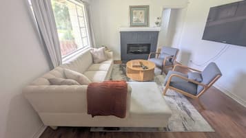 A living room with a sofa, armchairs, a coffee table, a fireplace, and a television.
