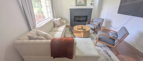 Una sala de estar con un sofá, sillones, una mesa de centro, una chimenea y un televisor.