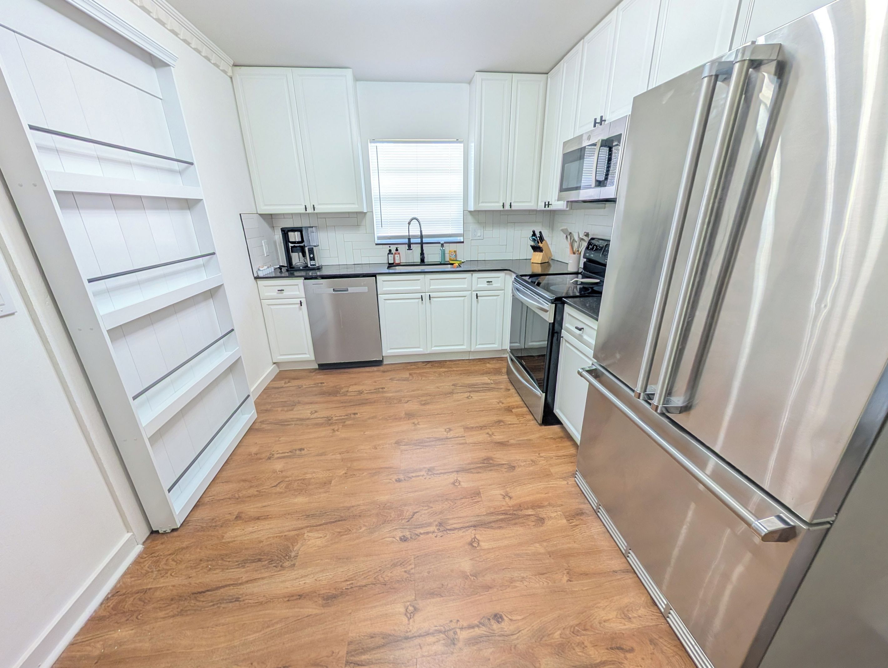 Una cocina con gabinetes blancos, un refrigerador de acero inoxidable y un lavavajillas.