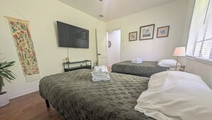 Een hotelkamer met twee bedden, een flatscreen televisie, een wandtapijt en een raam met zonwering.