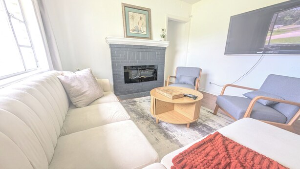 Een woonkamer met een open haard, een bank, een fauteuil en een televisie.