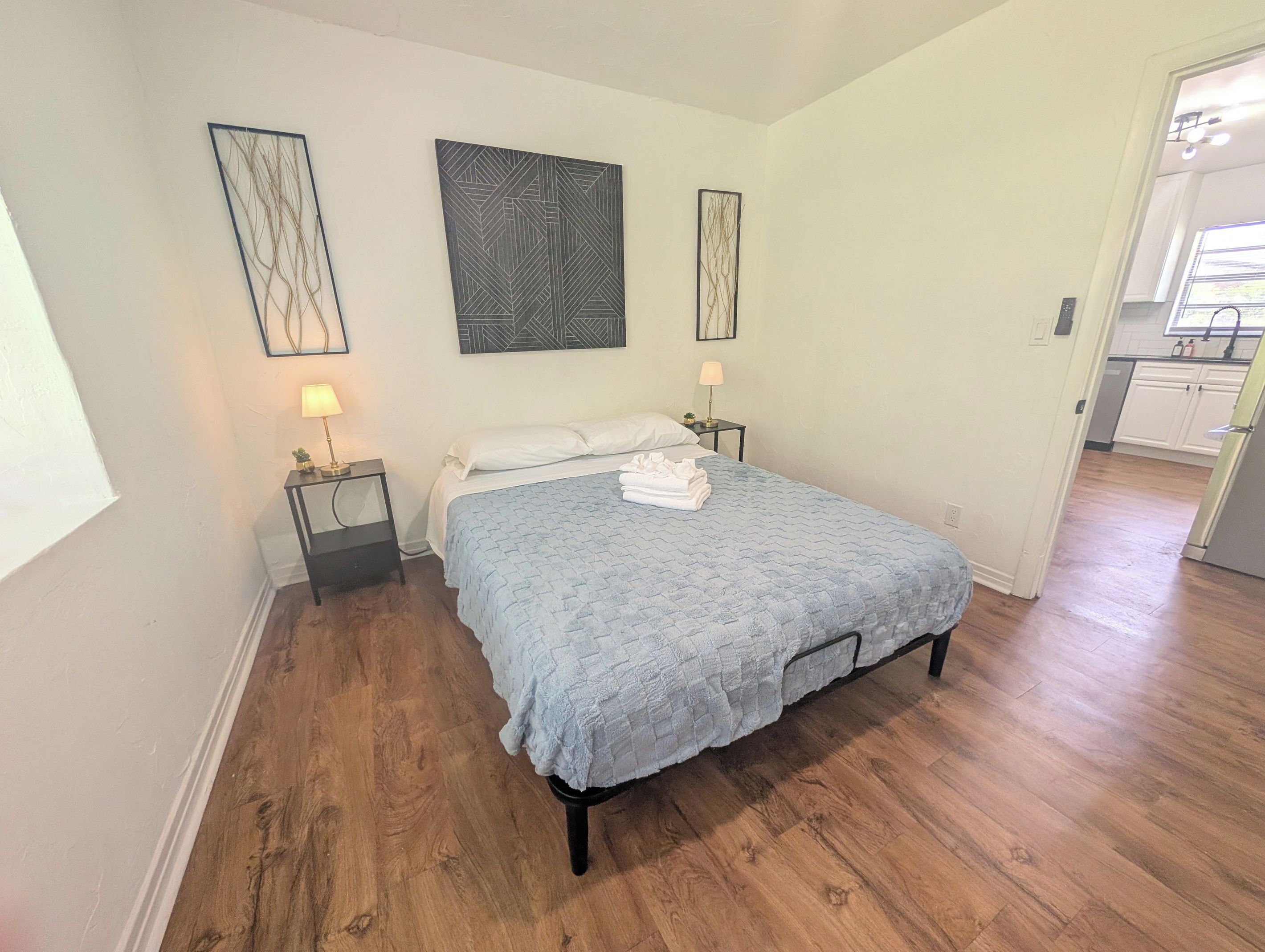 A bedroom with a bed, two bedside tables, and artwork on the walls.