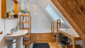Une petite salle de bain avec un puits de lumière, des étagères en bois, un lavabo et un espace douche.