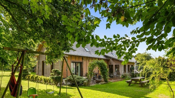 Une maison avec une façade en briques, une pelouse bien entretenue et un portique.