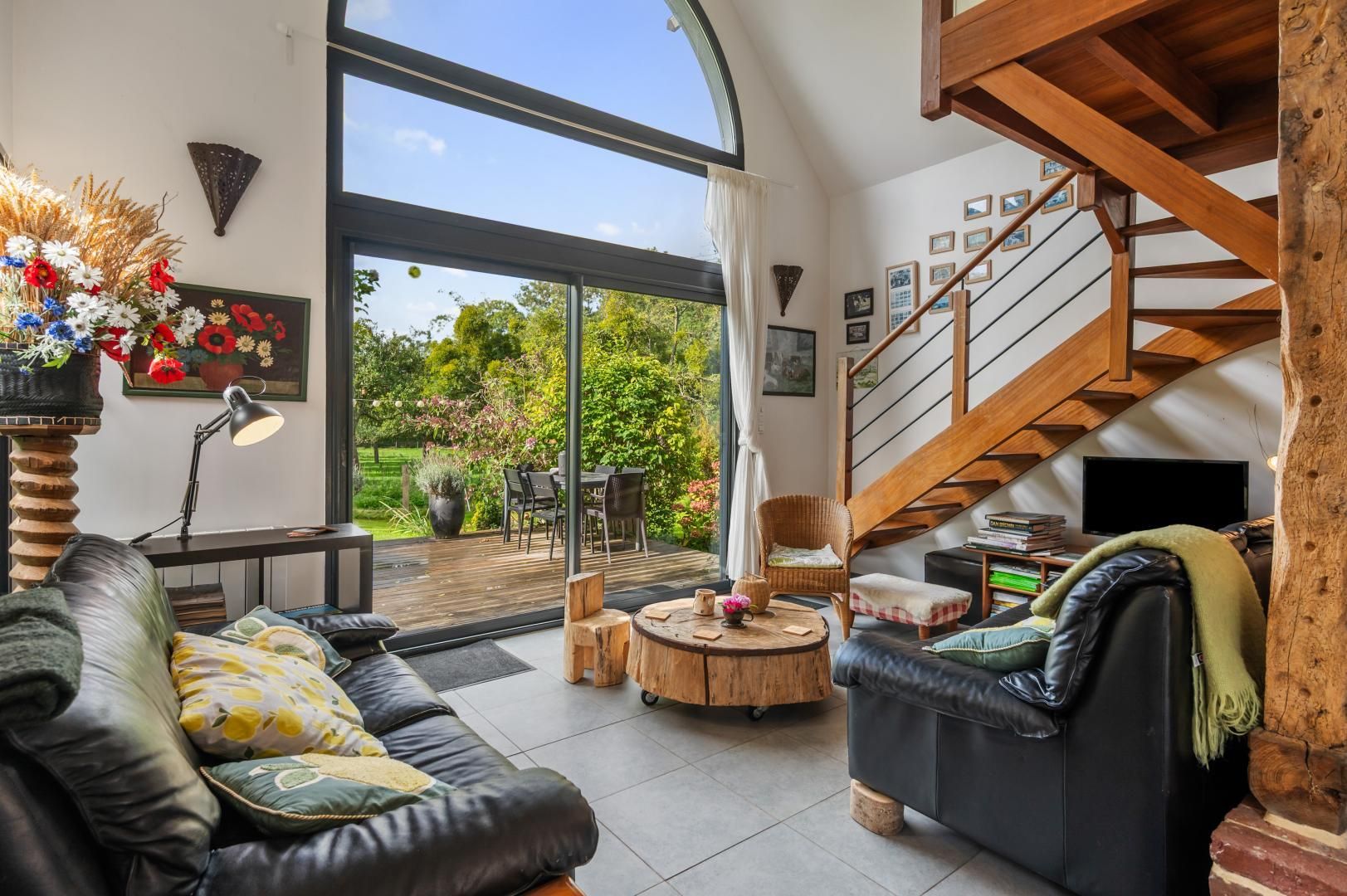 A spacious living area with a large window, a wooden staircase, and a cozy seating arrangement.