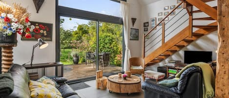 A spacious living area with a large window, a wooden staircase, and a cozy seating arrangement.