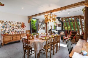 Um espaço de refeições acolhedor com uma mesa de madeira posta para quatro pessoas, rodeada por cadeiras.