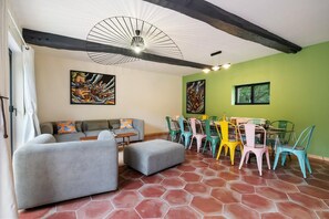 A room with a sofa, ottoman, dining table with chairs, and artwork on the walls. - Gîtes de France® - Gîte de la Ferme de Canteleu (LUNERAY)