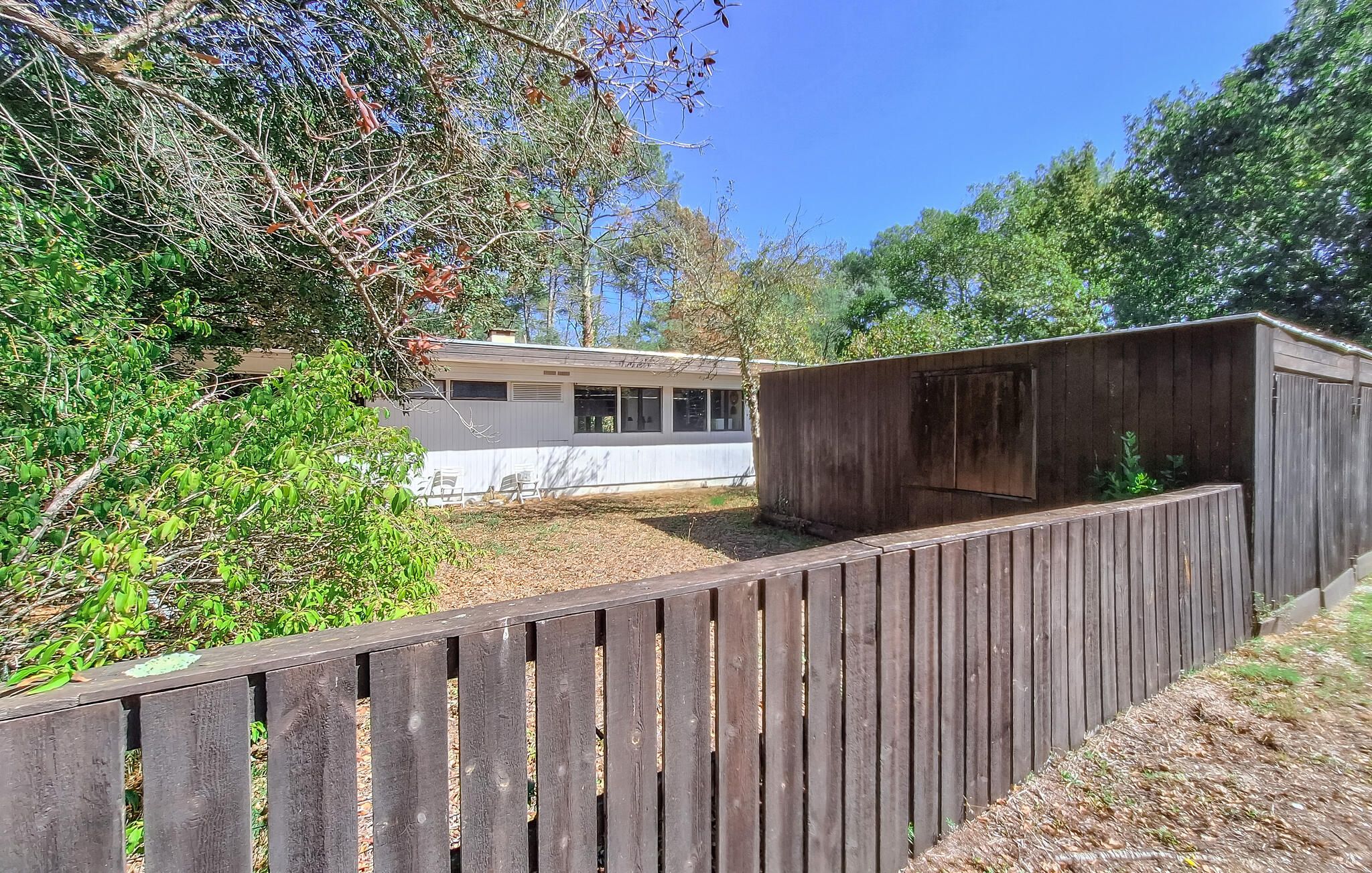 A fenced backyard with a wooden shed and a mobile home.