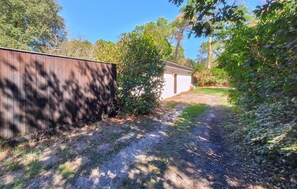 A gravel path leading to a building with a wooden fence on one side and dense foliage on the other. - 3 bedroom amazing home in Lacanau (Lacanau)