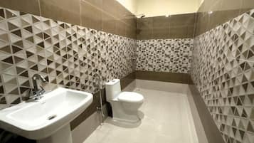 A bathroom with a sink, toilet, and shower. The walls have a geometric tile pattern.