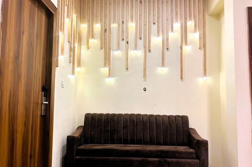 A wooden door, a wall-mounted light fixture with multiple bulbs, and a dark-colored sofa.