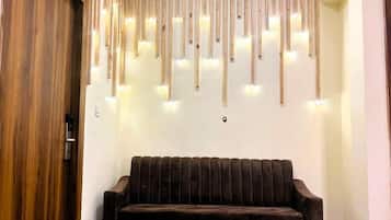 A wooden door, a wall-mounted light fixture with multiple bulbs, and a dark-colored sofa.