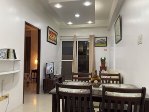 A dining area with a table and chairs, a television, and a potted plant.