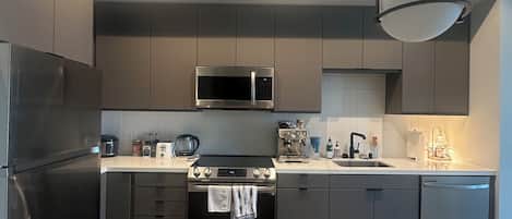 A modern kitchen with stainless steel appliances, a central island, and pendant lighting.