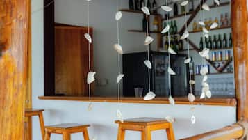 Un espace bar avec des meubles en bois et une décoration suspendue composée de coquillages blancs.