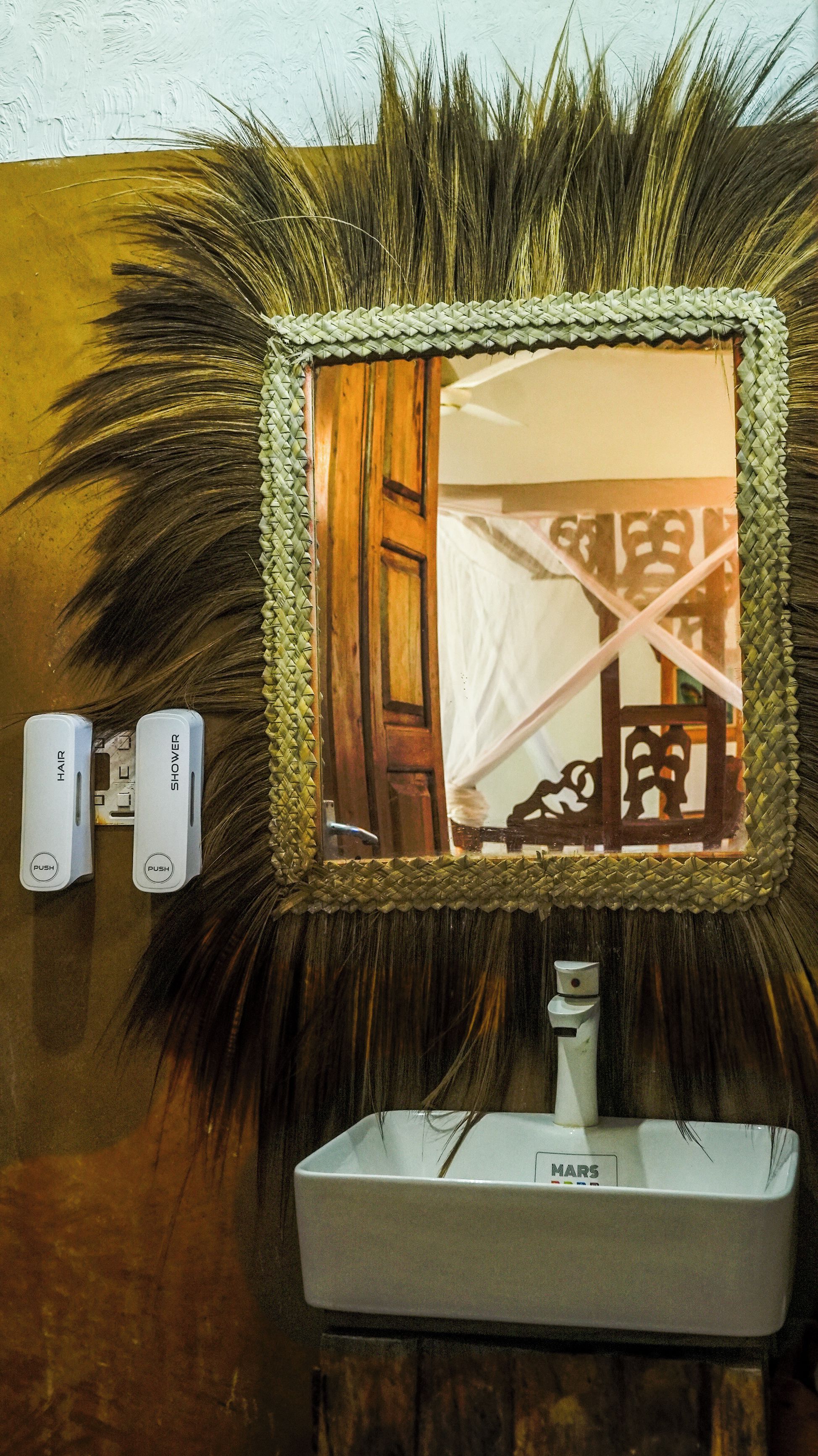 Un baño con espejo, lavamanos y dos controles en la pared, etiquetados 'HAIR' y 'SHOWER'.