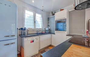 Eine kleine Küche mit Kühlschrank, Spüle und einem Fenster.