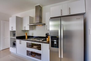 A modern kitchen with a stainless steel refrigerator, built-in oven, and gas stove. - Tortuga B50 - 5BR villa with private pool in beach resort (Punta Cana)