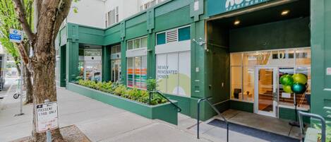 A building with a green facade, a sign for 'noda apartments,' and a 'newly renovated homes' advertisement.