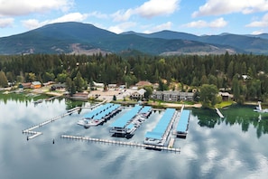 A marina with docked boats, surrounded by forested hills and a clear sky.