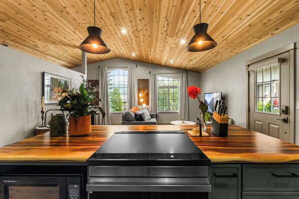 A modern kitchen with a wooden ceiling, large windows, and a central island.