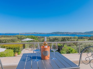 A terrace with a table set for two, a wine bottle, and two glasses. - GRIMAUD VILLA  WITH AN AMAZING SEAVIEW AND SWIMMING POOL (GRIMAUD)