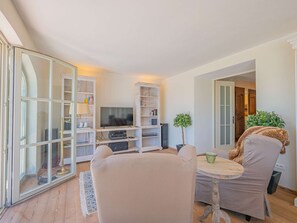 Un salon moderne avec un téléviseur, des étagères, une table à manger et des chaises.