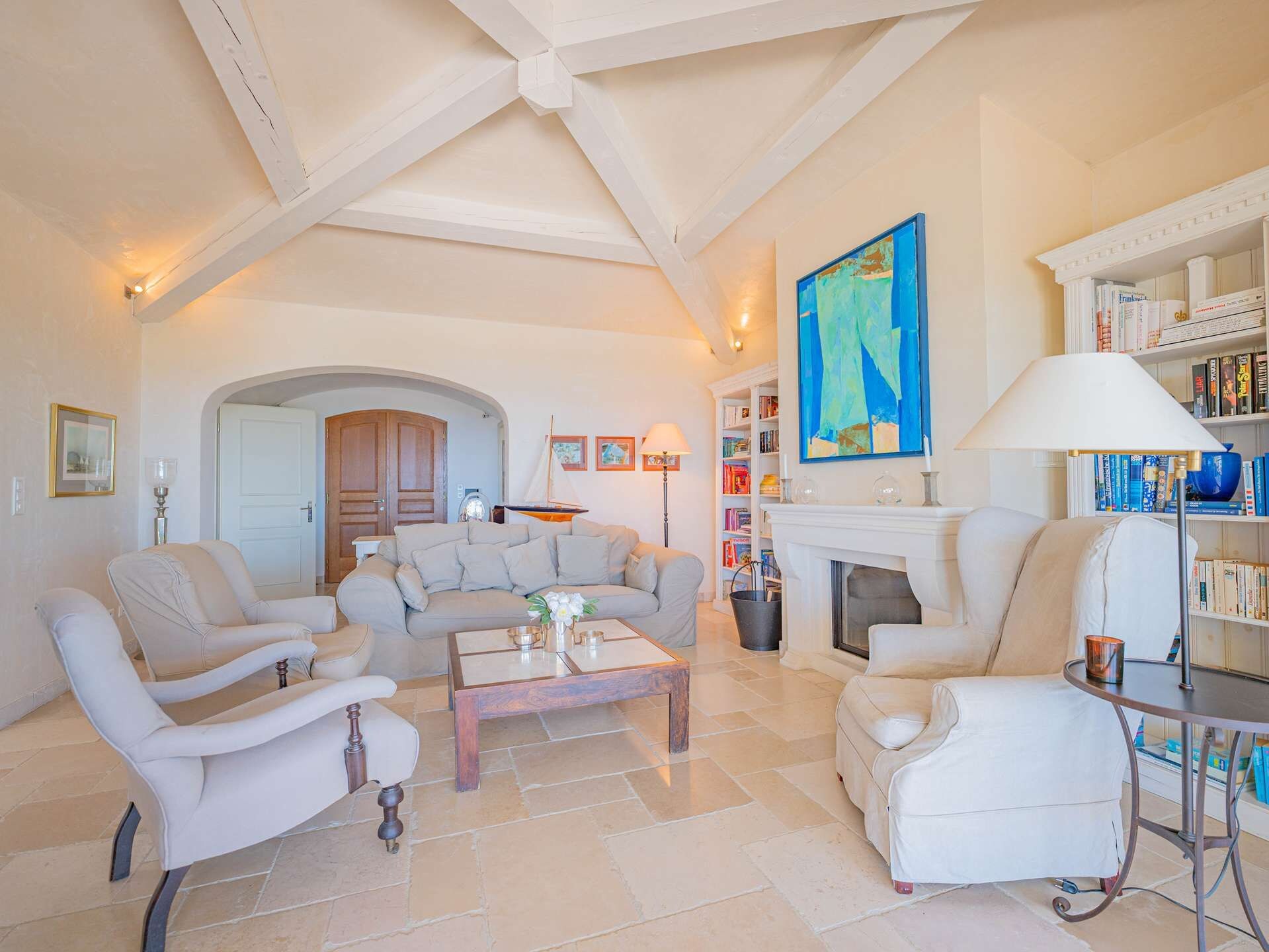 A spacious living room with a fireplace, a bookshelf, and a large abstract painting.