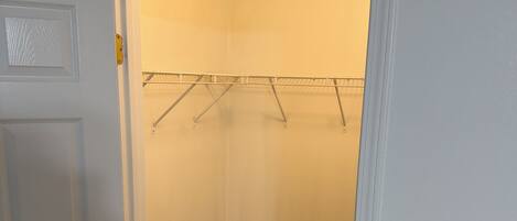 Um closet amplo com piso de madeira e um varal de metal.