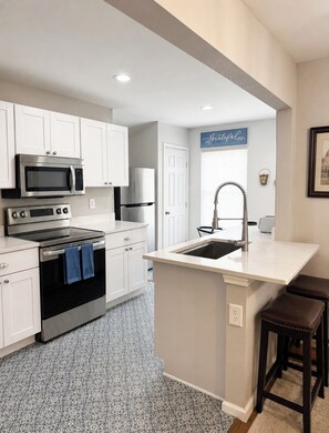A modern kitchen with white cabinetry, stainless steel appliances, a built-in oven, and a large island with a sink. - Tranquil 3-bedroom house with AC in San Antonio (San Antonio)