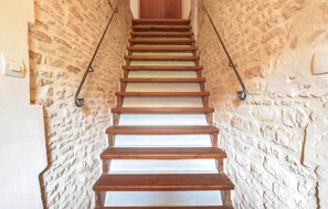 Una escalera de madera flanqueada por paredes de piedra, que conduce a una puerta de madera en la parte superior.