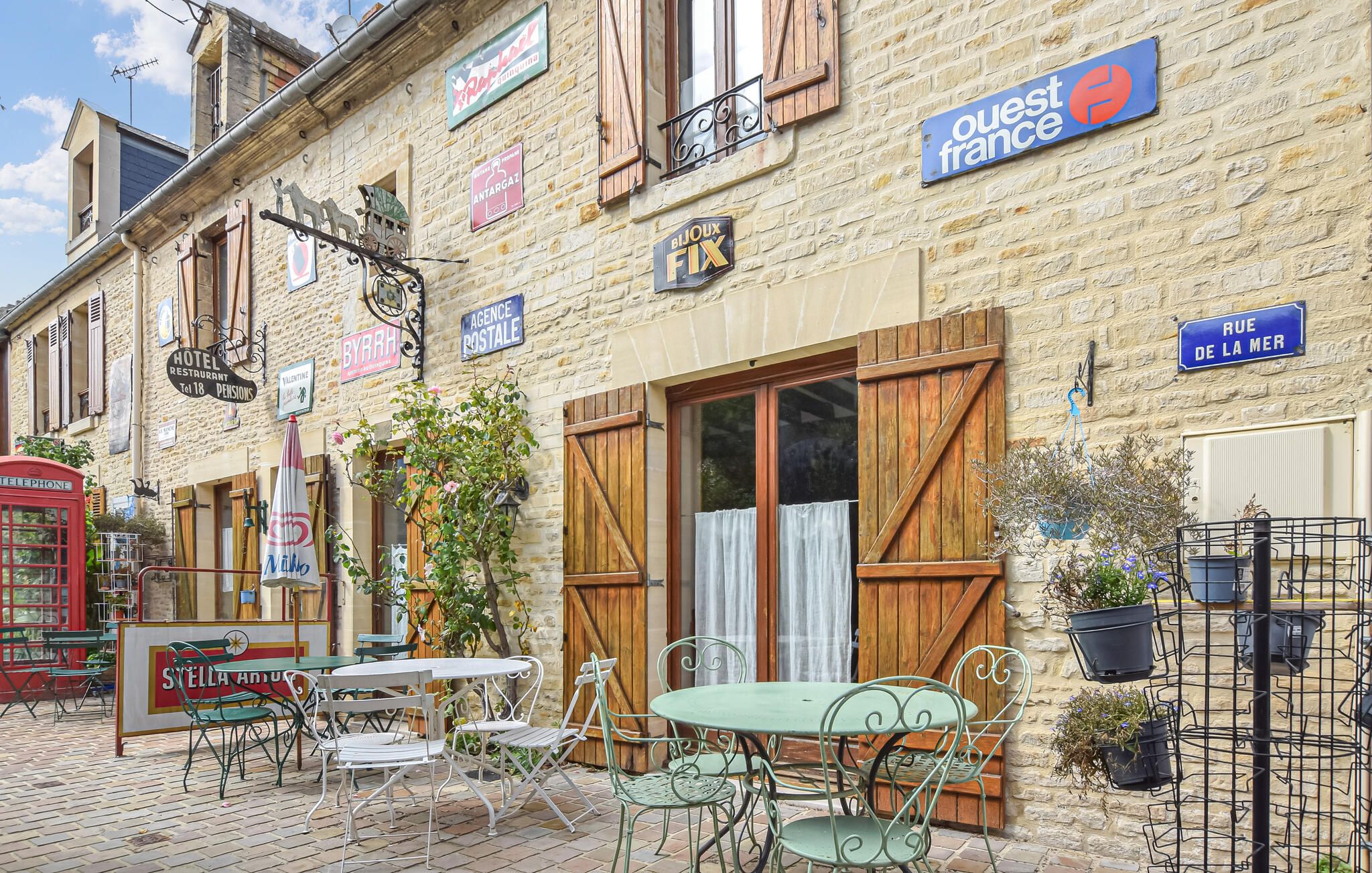 Una calle europea pintoresca con un hotel llamado 'Stella Artois' y un restaurante 'Byrrh'.