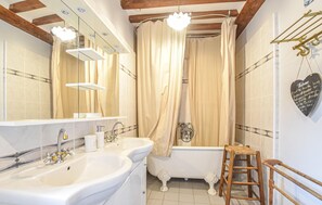 Une salle de bain avec une baignoire, deux lavabos, un miroir et un rideau de douche.