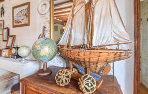 Un modelo de barco sobre una mesa de madera, un globo terráqueo y cuadros en la pared.