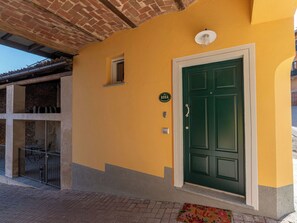 Ein Gebäude mit einer gelben Fassade, einer grünen Tür und einem kleinen Fenster.