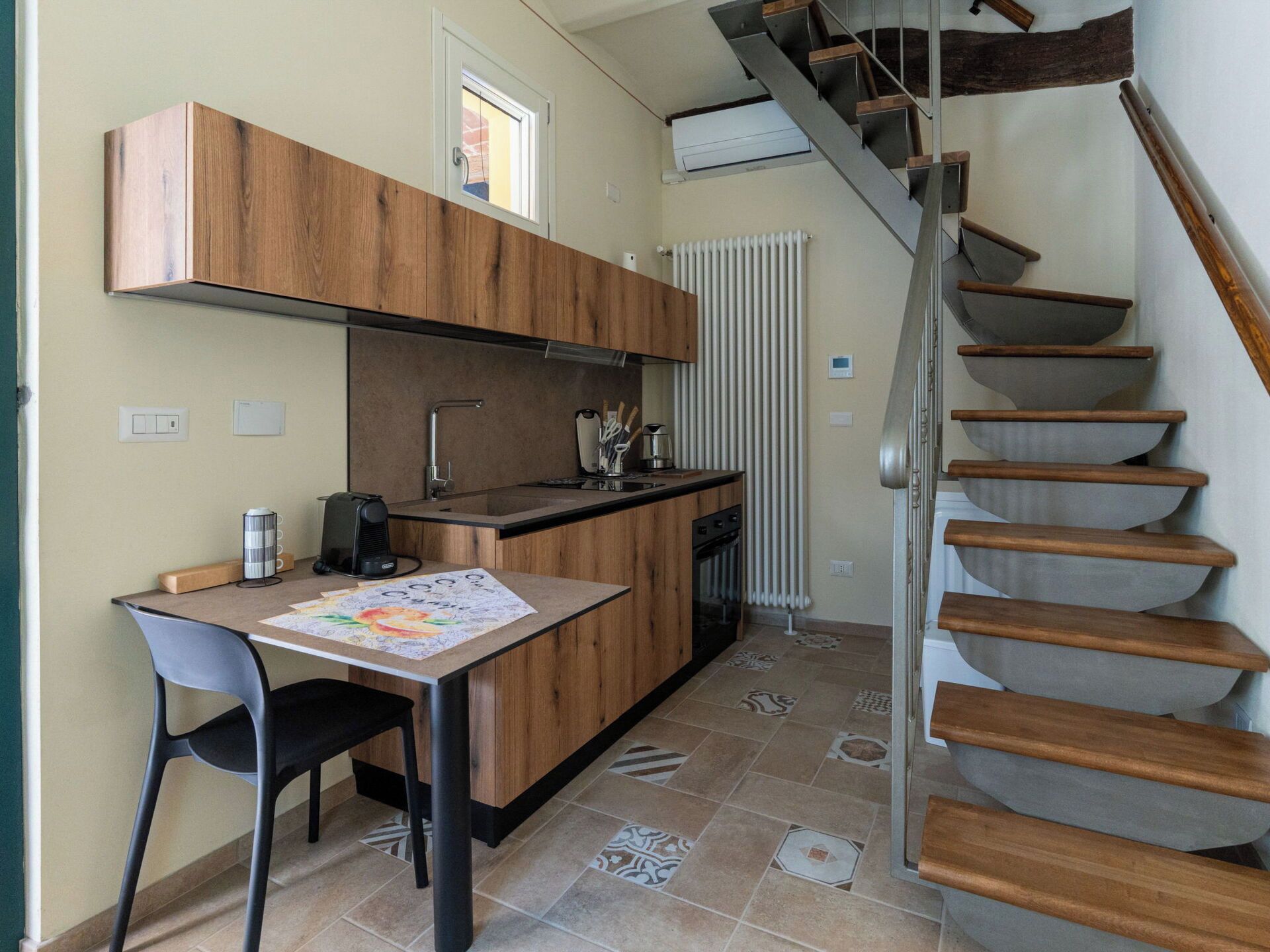 Une cuisine compacte avec un coin repas, une cuisinière intégrée et un escalier en bois.