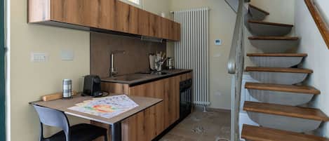 A compact kitchen with a dining area, a built-in stove, and a wooden staircase.