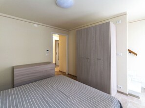 Een slaapkamer met een bed, een kast en een deur naar een andere kamer.